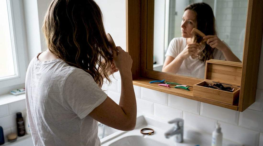 Une femme se coiffe dans sa salle de bain à l’aide de ses accessoires préférés.