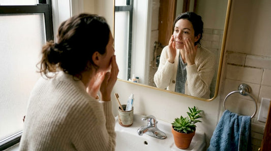 Une femme prend soin de sa peau en appliquant sa crème hydratante lors de sa routine matinale dans la salle de bain.