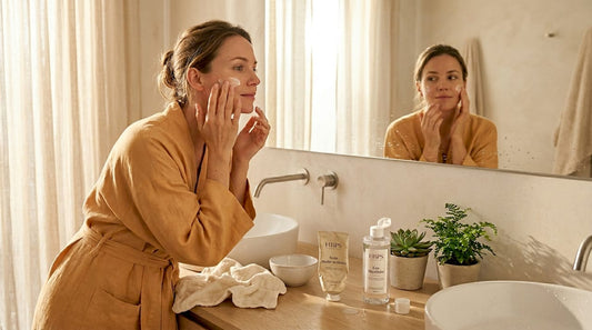 Une femme prend soin de sa peau avec un soin multifonctions dans sa salle de bain.