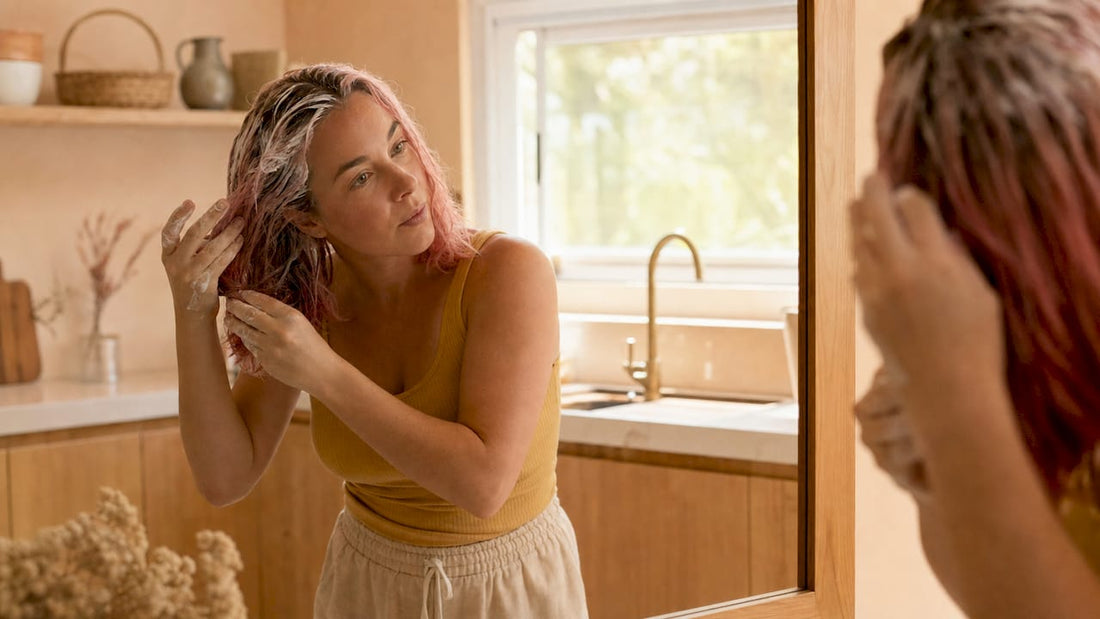 Une femme prend soin de ses cheveux colorés en appliquant un traitement réparateur.